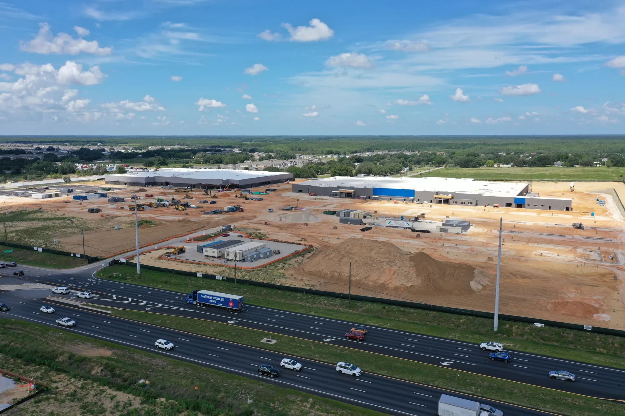 Aerial view of a large retail building and graded pad sites under construction beside US Highway 27 near Davenport, Florida