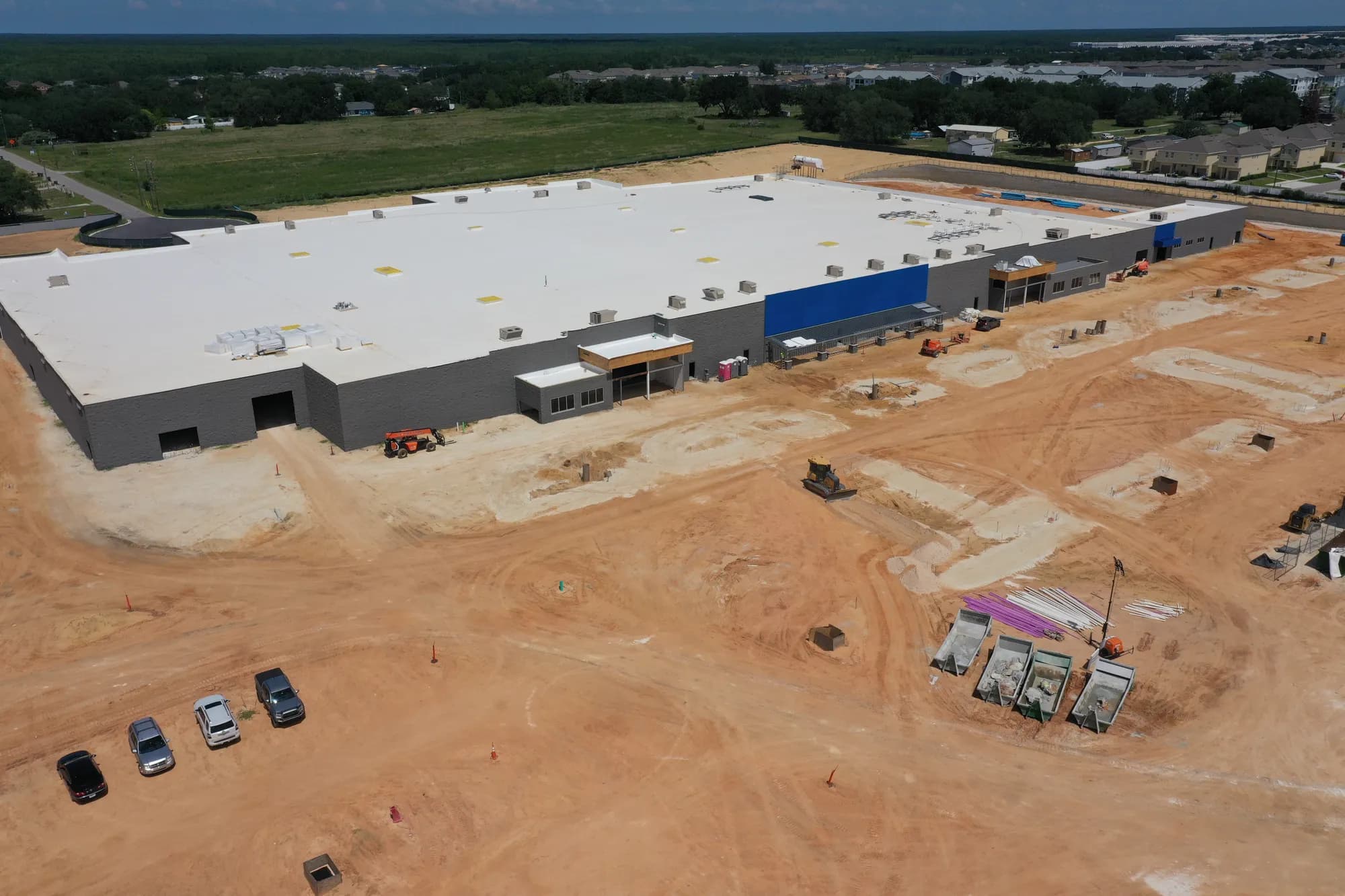 Aerial of the flat white roof of a big-box retail building and graded land around it