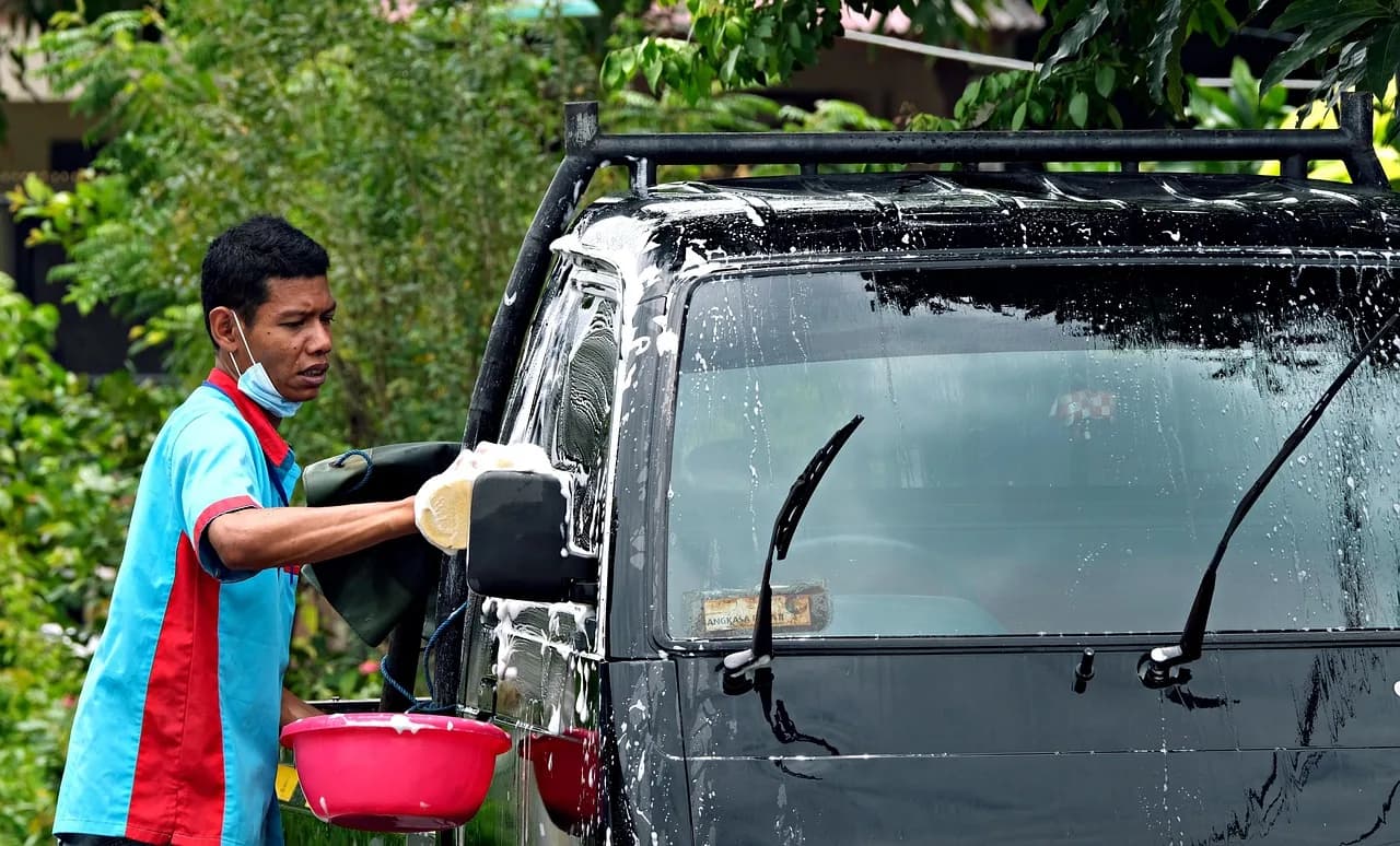 Car wash attendant cleaning a vehicle at a Florida wash bay